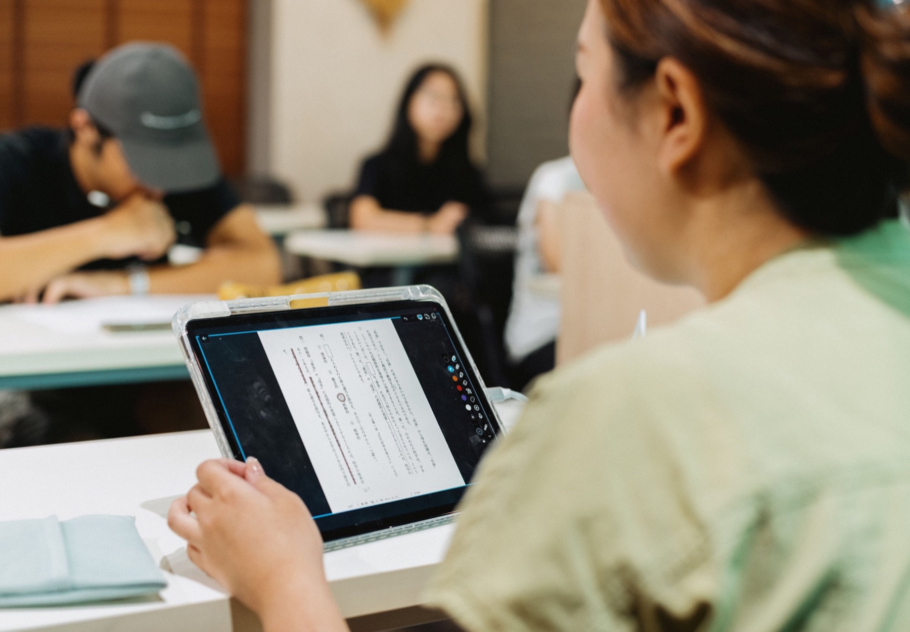 タブレットを囲んで話し合う日本の学生たちのイメージ写真